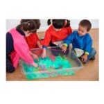 Imagen de varios niños jugando en la bandeja transparente para agua y arena