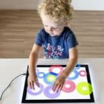 Niño jugando con los anillos translúcidos de texturas con plantillas en la mesa de luz