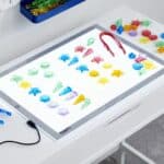 Mesa de luz encendida con las conchas translúcidas de colores colocadas encima y clasificadas por tipo.