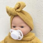 Detalle de la cabeza de la Muñeca Bobble mostaza de 26 cm con el chupete puesto