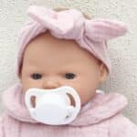 Detalle de la cabeza de la Muñeca Bobble rosa de 26 cm con el chupete puesto