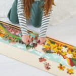 Niña jugando con el Puzzle panorámico de la prehistoria de 100 piezas