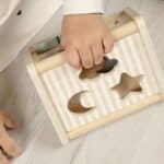 Niña jugando con el triángulo de actividades 3 en 1 incluido en la Caja Juega y aprende 18-24 meses, set de 4 juguetes