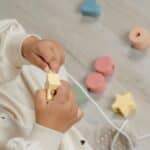 Niña jugando con las piezas para ensartar incluidas en la Caja Juega y aprende 18-24 meses, set de 4 juguetes