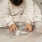 Niña jugando con el puzzle reversible incluido en la Caja Juega y aprende 18-24 meses, set de 4 juguetes
