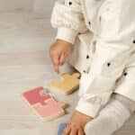 Niña jugando con el puzzle reversible incluido en la Caja Juega y aprende 18-24 meses, set de 4 juguetes