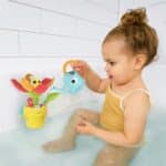 Niña en la bañera jugando con Cucú, abeja y flor juguete de agua para la bañera