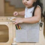 Niña sentada en la torre de aprendizaje y cogiendo una pintura de la Bolsa estuche de fieltro Pencil Pocket