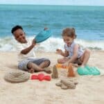 Niño y niña jugando en la playa con los Moldes para hacer naves espaciales de arena con mochila antiarena
