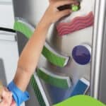 Niño jugando en una nevera con el Tumble Trax, circuito magnético de canicas