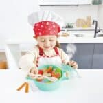 Niña con gorro y delantal de chef revolviendo los ingredientes del Juego de cocina Little chef, olla con vapor