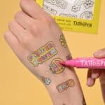12 tatuajes temporales para colorear 70s colocados en una mano