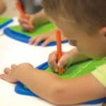 Niñas y niños en un aula utilizando la Bandeja con punzón de preescritura, set de 4
