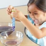 Niña jugando feliz con la pipeta de las Herramientas de motricidad fina para agua y arena
