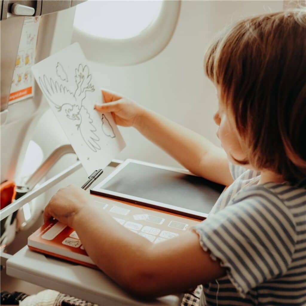Niña utilizando la Tableta de dibujo con plantillas Kidydraw mini en un avión