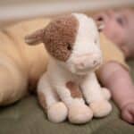 Bebé al lado del Peluche vaca 17 cm pequeña granja Little Dutch
