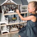 Niña jugando con la Casa de muñecas de madera con muebles Villa en la ciudad