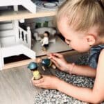 Niña jugando con la Casa de muñecas de madera con muebles Villa en la ciudad