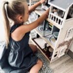 Niña jugando con la Casa de muñecas de madera con muebles Villa en la ciudad
