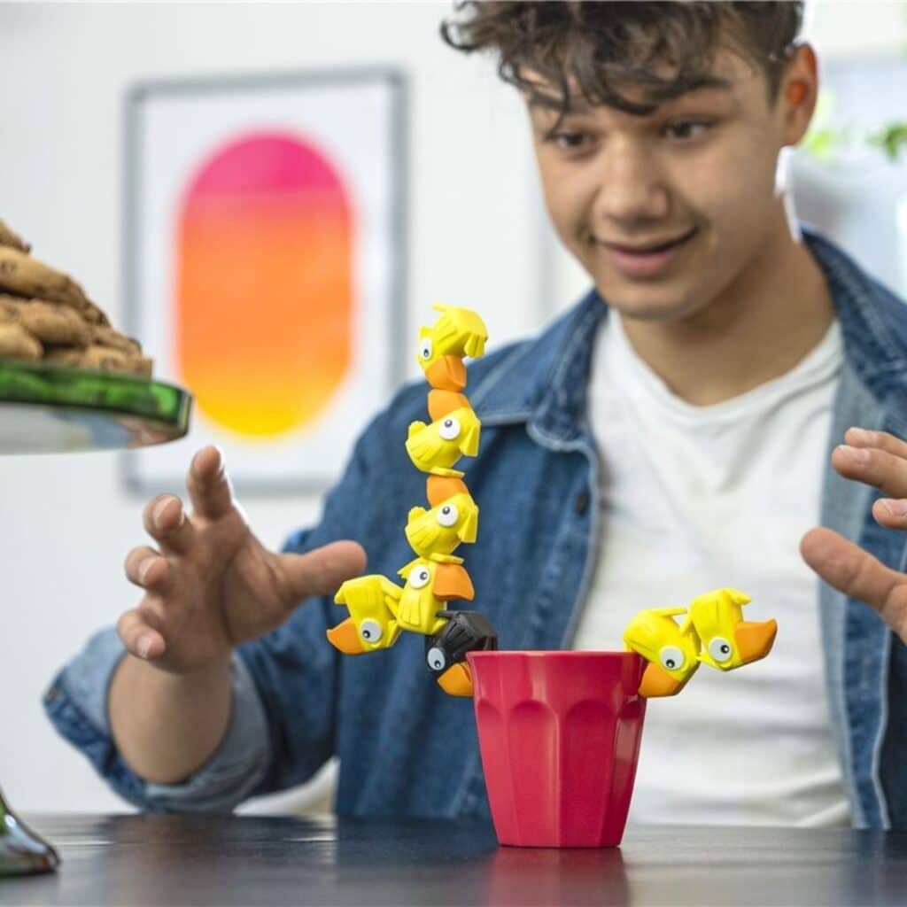 Chico jugando con el Juego de equilibrio de apilar Torre tucán figuras amarillas