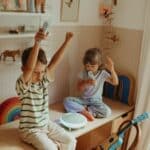 Niña y niño emocionados cantando con el Altavoz karaoke portátil con dos micrófonos Kidykaraoke
