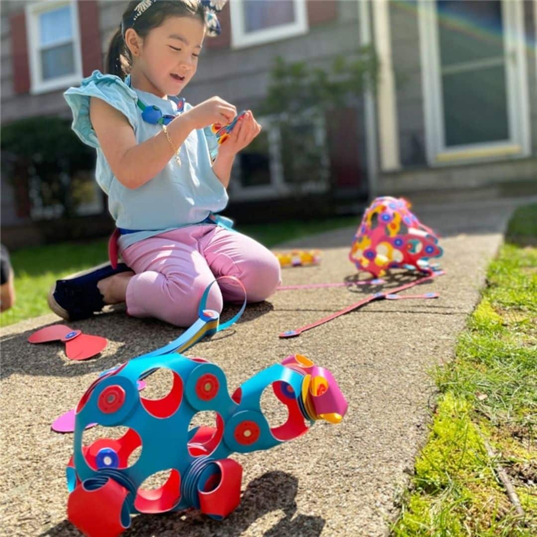 Niña jugando en la calle con la Construcción magnética 30 piezas flexibles Clixo Crew pack rosa/amarillo