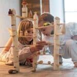Niño y niña jugando en el suelo con las Piezas de construcción de madera Woodland de Grapat