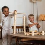 Dos niños jugando en una mesa con las Piezas de construcción de madera Woodland de Grapat