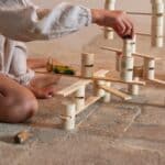 Detalle de una mano jugando con las Piezas de construcción de madera Woodland de Grapat
