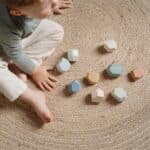 Niño sentado en una alfombra jugando con las Rocas de madera para apilar Forest Friends de Little Dutch