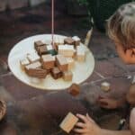Niño jugando con la Tabla de equilibrio y piezas de madera El péndulo de Grapat