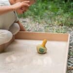 Niño jugando con el Tentetieso peonza pájaro Flowing yellow bird de Grapat en un arenero