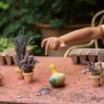 Niño jugando con el Tentetieso peonza pájaro Flowing yellow bird de Grapat en una mesa de jardín con plantas
