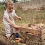 Un niño pequeño haciendo una torre con piedras y las piezas de la Torre apilable Serendipity de Grapat