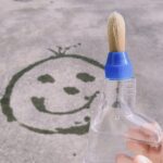 Carita sonriente en el suelo pintada con agua gracias al pincel que se engancha en envases reutilizables