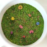 imagen de una bandeja sensorial con fideos verdes y las Miniaturas mix de primavera de Mundo Safari