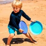 imagen de un niño jugando en la playa con el frisbee morado