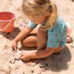 imagen de una niña jugando con los moldes del Set de juguetes de playa cubo naranja de Monnëka