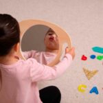 Imagen de una niña mirándose en Espejo con asa de madera grande