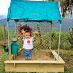 imagen de una niña dentro del arenero de la Cabaña con arenero de madera Sandbox de Hape
