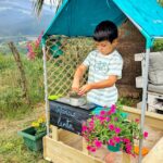 imagen de un niño jugando con los elementos de la Cabaña con arenero de madera Sandbox de Hape