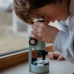 Iamgen de niño mirando por Microscopio portátil con luz Kidymicroscope verde