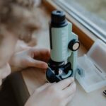 Imagen de manos de niño con Microscopio portátil con luz Kidymicroscope verde