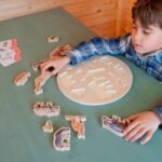 Imagen de niño jugando con Puzzle con imágenes reales selva y tarjeta informativa