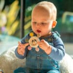 imagen de un bebé jugando con el Sonajero mordedor de madera y silicona Tierra de Tickit