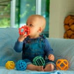 imagen de un bebé jugando con el Set de 5 pelotas sensoriales de silicona arcoíris de Tickit