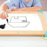 imagen de un niño pintando en la pizarra del Laberinto magnético y tablero de Tangram de Hape