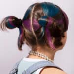 imagen de un niña con moños pintados con ls Tizas temporales para el pelo de Omy