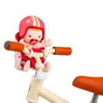 imagen de la Muñeca blandita Lena con asiento para bicicleta de Janod en el manillar de una bicicleta