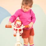 imagen de una niña con la Muñeca blandita Lena con asiento para bicicleta de Janod